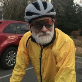 gray bearded cyclist in a yellow windbreaker